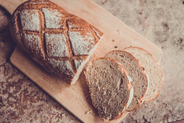 Bread slice on a wooden board. Wheat fresh loaf - Foto, Bild