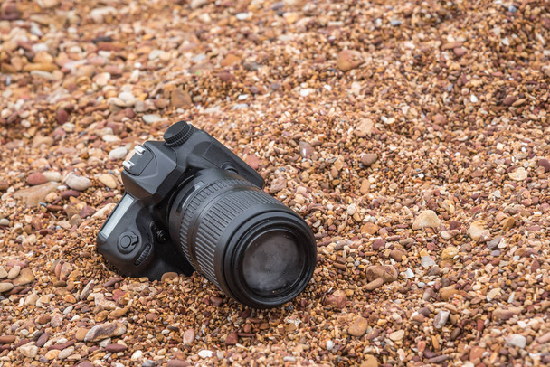 DSLR fotocamera sulla spiaggia di pietra bagnato da onda di mare d'acqua
 - Foto, immagini