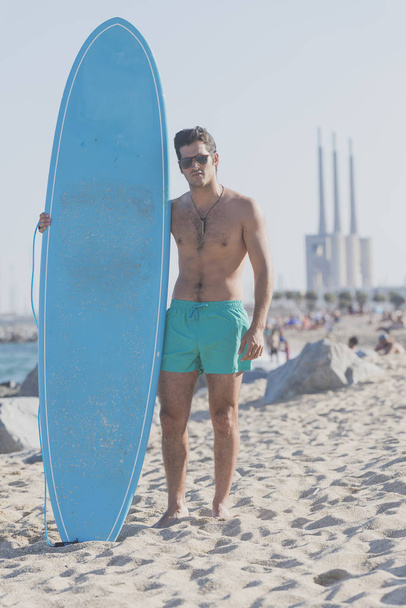 Surfer holding his blue surfboard - Foto, imagen