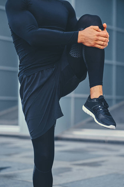 Sportieve man is stretching zijn benen - Foto, afbeelding