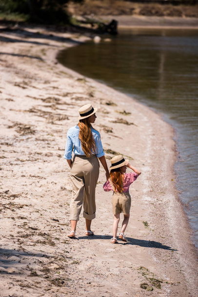 mother and daughter walking at seashore - Фото, изображение