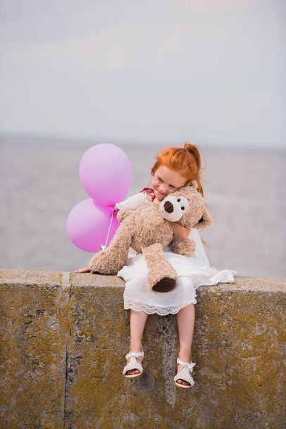 child with teddy bear and balloons - Фото, изображение