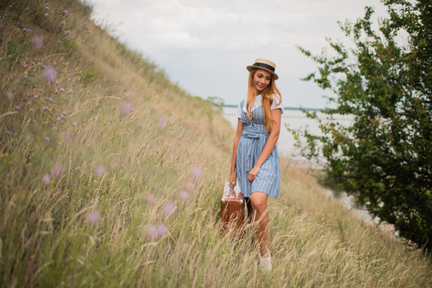 girl with suitcase on grassland - Фото, зображення