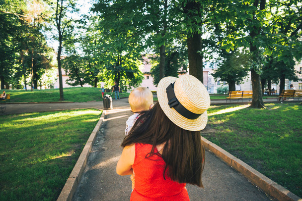 donna passeggiare al parco con il bambino tra le braccia
 - Foto, immagini