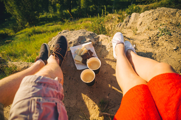 man and woman legs on the top of the hill with two cups and chocolate - Fotografie, Obrázek
