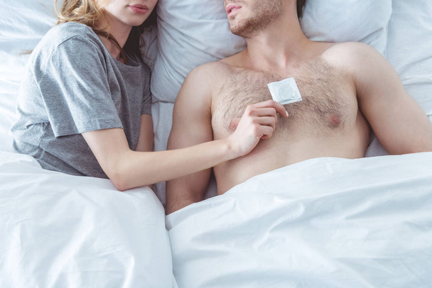 couple with condom in bed - Foto, afbeelding