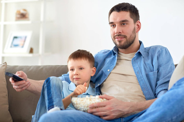 father and son with popcorn watching tv at home - Foto, Imagem