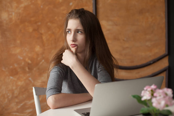 girl with laptop typing and thinking - Φωτογραφία, εικόνα