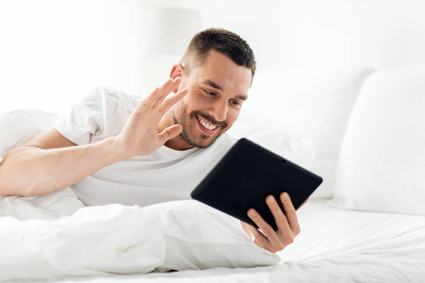 man with tablet pc having video call in bed - Фото, изображение