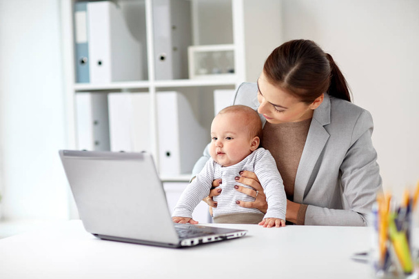 happy businesswoman with baby and laptop at office - Foto, Imagen