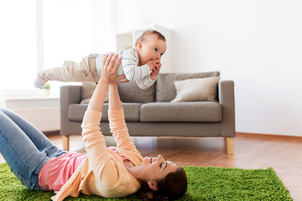 happy young mother playing with baby at home - 写真・画像