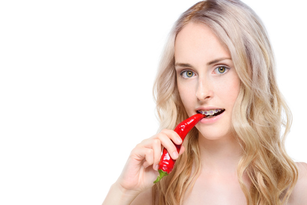 Woman taking bite of chili pepper - Fotoğraf, Görsel