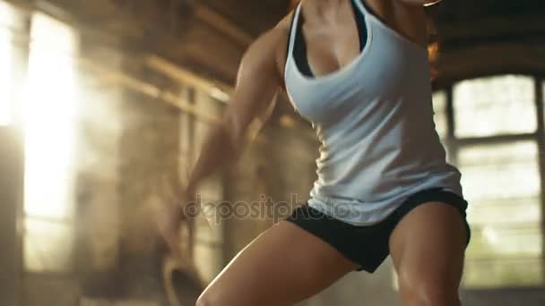 Sportovní holka aktivně v tělocvičně cvičení s bitva lana během její Cross Fitness cvičení / High intenzita intervalový trénink. Ona je sval a zpocené, tělocvična je v opuštěné továrně. - Záběry, video