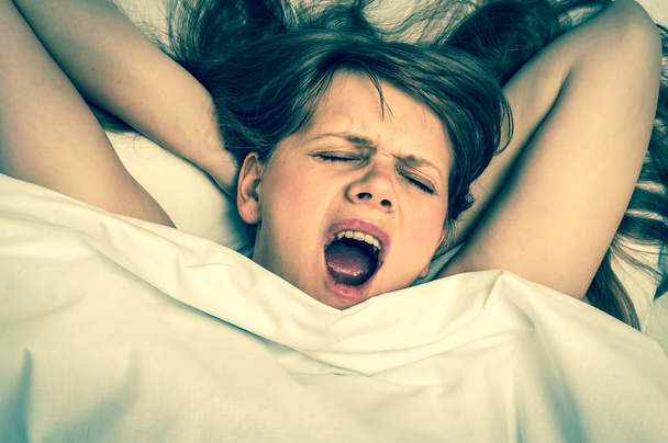 Молода жінка позіхає в ліжку після сну - ретро стиль
 - Фото, зображення