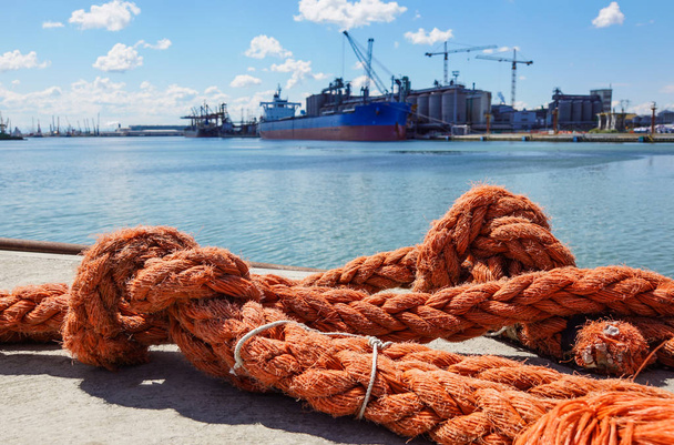 Cuerda de amarre y pilona en agua de mar
 - Foto, imagen