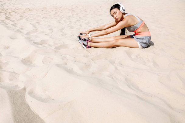sportswoman stretching on sand - Фото, изображение