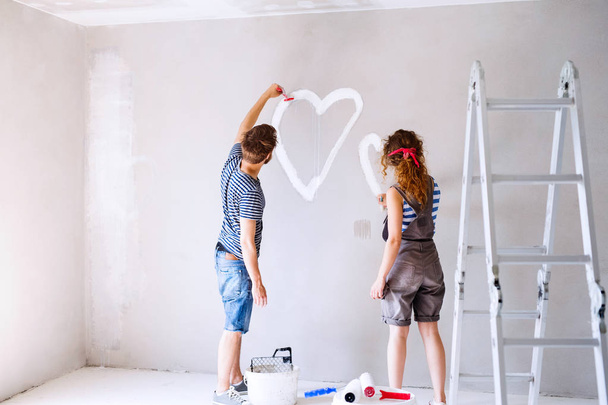 Couple painting heart on the wall in their house. - Fotoğraf, Görsel