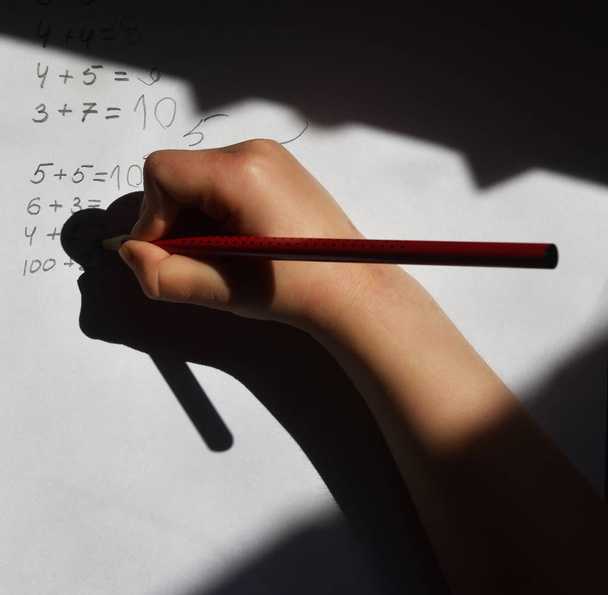 children's hand with a pencil solves mathematical examples - Photo, Image