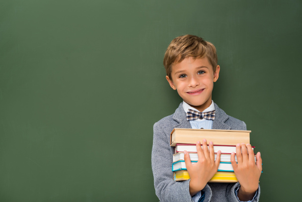smiling schoolboy with stack of books - Foto, imagen