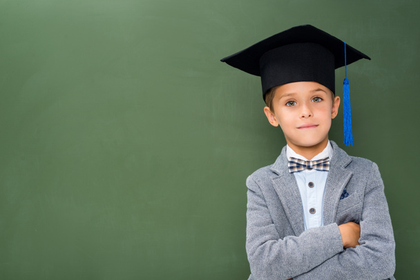 школьник в выпускной шляпе со скрещенными руками
 - Фото, изображение