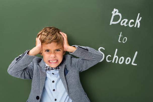 angry schoolboy holding his head - Photo, Image