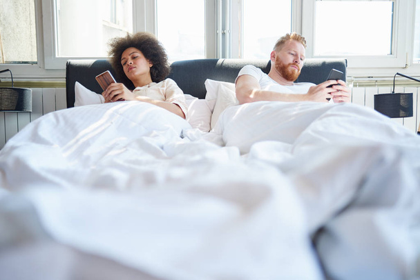 couple using mobile phones in bed  - 写真・画像