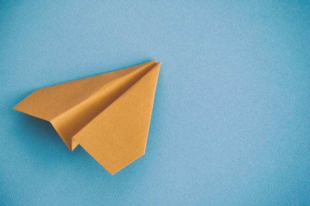 Yellow paper plane on a blue background - Foto, imagen