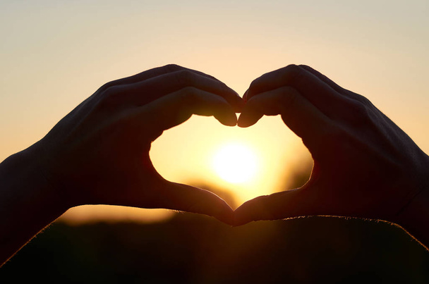 La silhouette del cuore delle mani al centro del suo Sole. Il concetto di amore e felicità
 - Foto, immagini