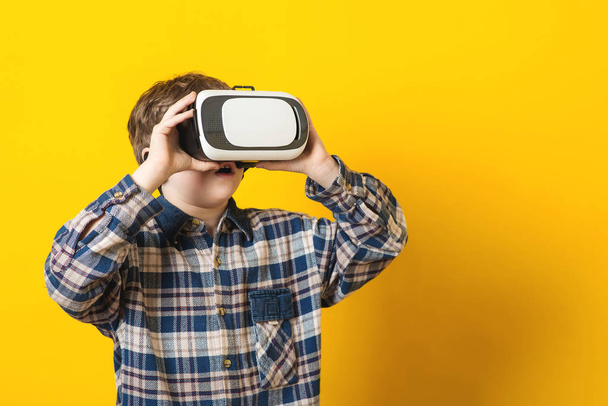Chłopiec w wirtualnej rzeczywistości gogle na żółtym tle. - Zdjęcie, obraz