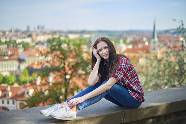 Мечтательная девочка-подросток в Праге сидит на парапете
 - Фото, изображение