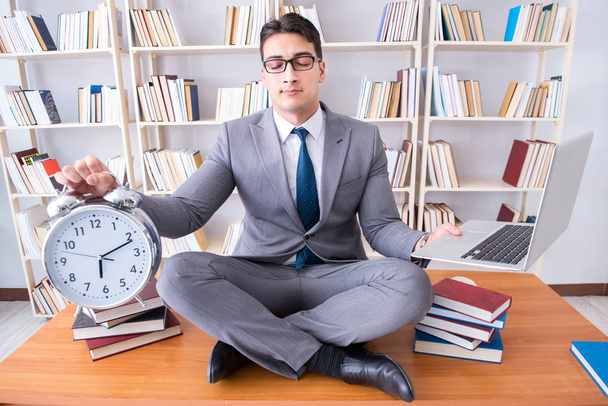 Бизнесмен студент в позе лотоса с будильником и - Фото, изображение