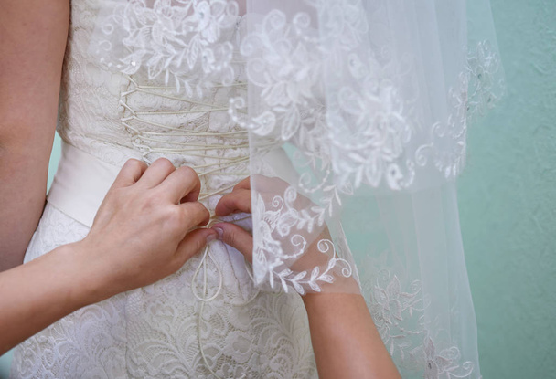 Bridesmaid helps to bride dress in wedding day - Fotó, kép