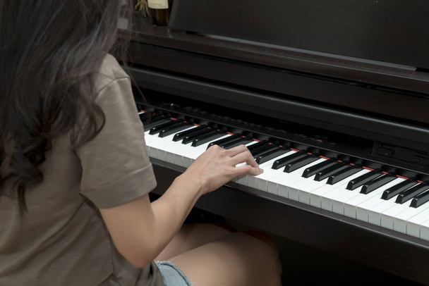 Side view of Young woman playing piano - 写真・画像