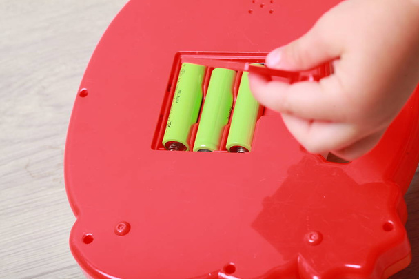 mano el niño puso las baterías en el juguete rojo
 - Foto, imagen