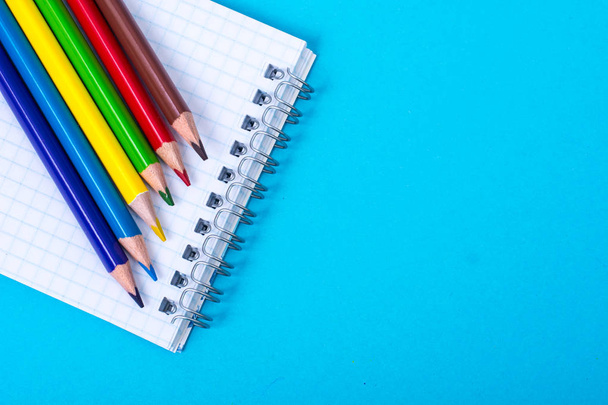 Notepad for notes and colorful pencils on colored background - Фото, зображення