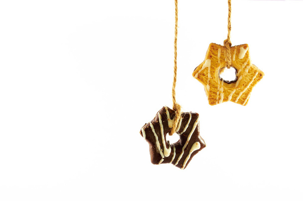 Keksi.Maito- ja suklaakeksit roikkuvat köydellä valkoisella pohjalla
 - Valokuva, kuva