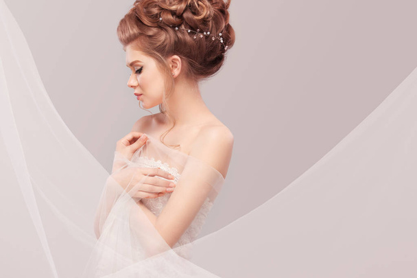 Beautiful bride with fashion wedding hairstyle - on gray background. Closeup portrait of young gorgeous bride. Wedding. Studio shot with copy space. - Foto, imagen