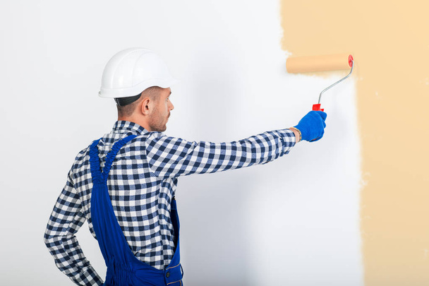 painter man painting wall in beige - Foto, afbeelding