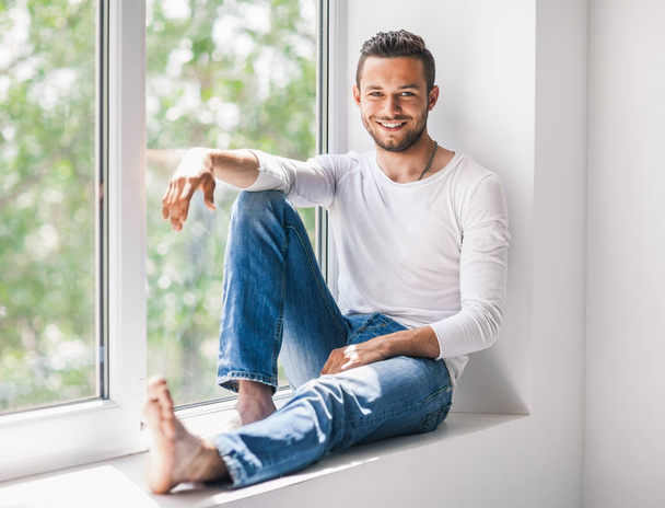 smiling man relaxing on window sill - Foto, imagen