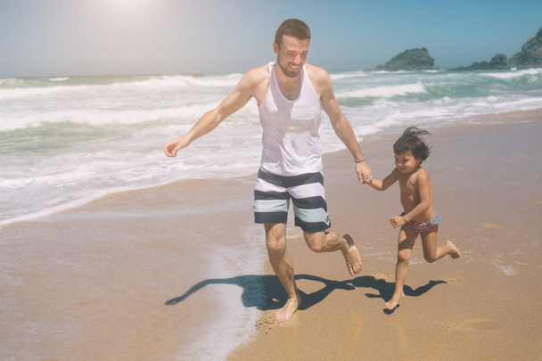 Happy father and his sweet little daughter at beach Playing Together at Sunset. Happy Fun Smiling Lifestyle - Photo, Image
