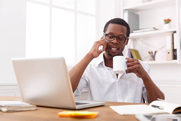Mladý černý podnikatel volání mobilní telefon v moderní bílé úřadu - Fotografie, Obrázek