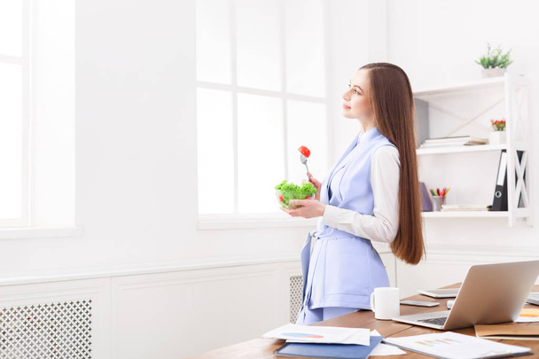 Nuori liiketoiminnan nainen syö salaattia toimistossa
 - Valokuva, kuva