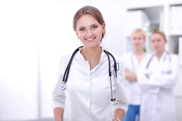 Young woman doctor standing at hospital with medical stethoscope - 写真・画像
