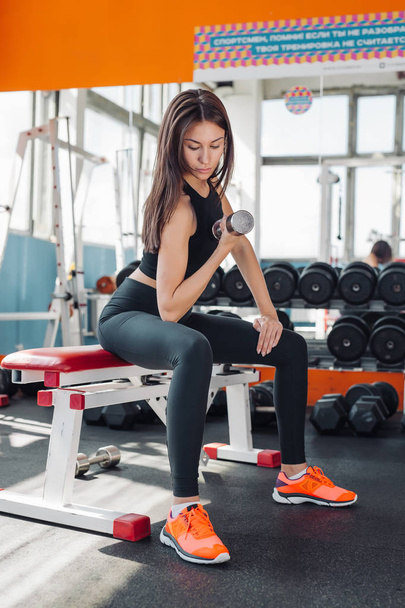 Fit woman 20s doing shoulder raises with dumbbells in gym - Foto, Imagen