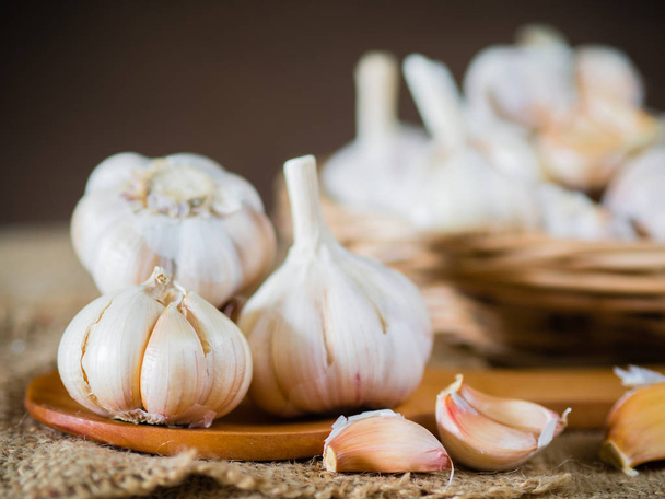 Closeup garlic clove, garlic bulb in wicker basket place on hemp sack background - 写真・画像