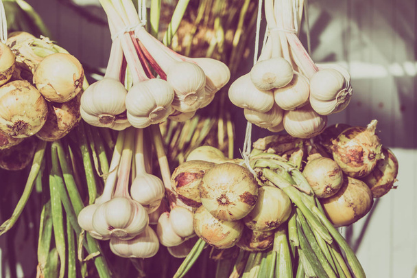 hängende Knoblauchzöpfe und Zwiebelbündel, Trocknen von Gewürzen und Bio-Gemüse aus biologischem Anbau von einheimischen Bauern - Foto, Bild