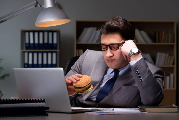Uomo d'affari a tarda notte mangiare un hamburger - Foto, immagini