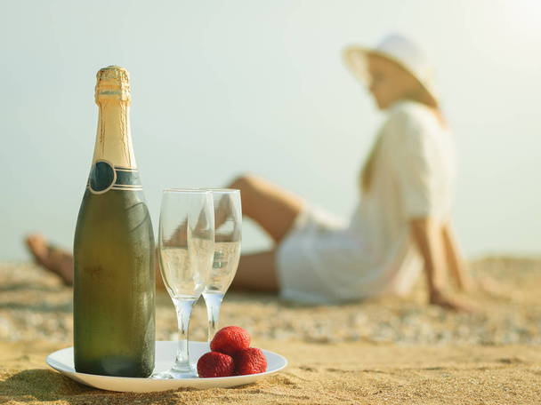 Una botella llena de chamanes, fresas y la mujer en la playa
. - Foto, Imagen