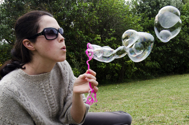 Молода жінка грає з бульбашковою паличкою
 - Фото, зображення