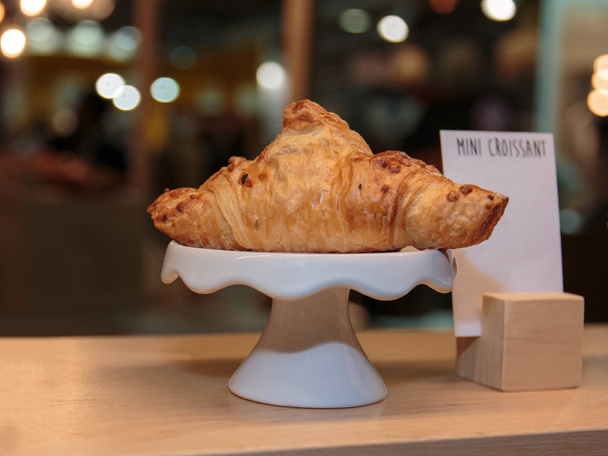 Čerstvý Croissant na bílé misce na dřevěné police - Fotografie, Obrázek